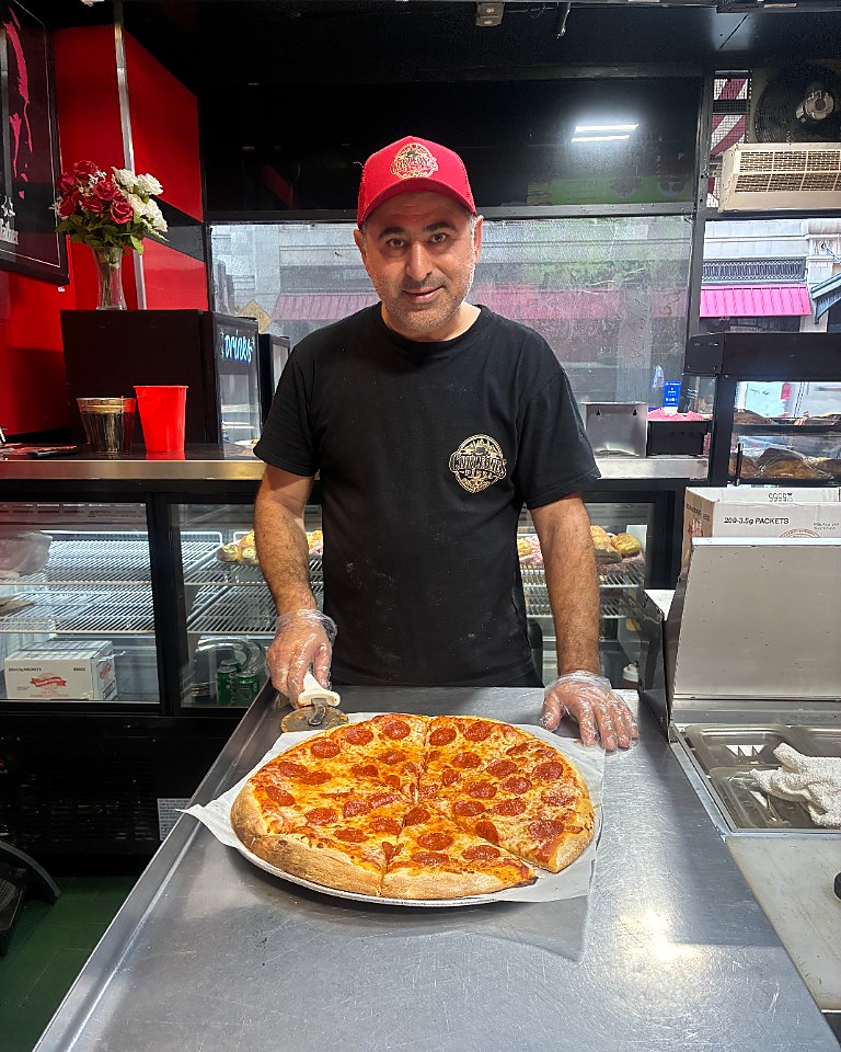 Arthur D., owner of Corleone Pizza, holding a fresh pepperoni pizza